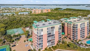 A high-rise hotel with multiple floors, a swimming pool, and a tennis court. - Palm Harbor #201 3 Bedroom Condo (Fort Myers Beach)