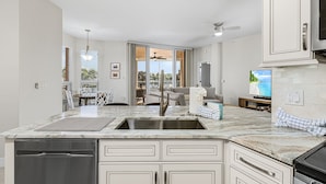 A modern kitchen with a large island, built-in appliances, and a view to a dining area. - Palm Harbor #201 3 Bedroom Condo (Fort Myers Beach)