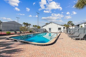 Una piscina rectangular con borde de azulejos, rodeada por un patio de ladrillo.