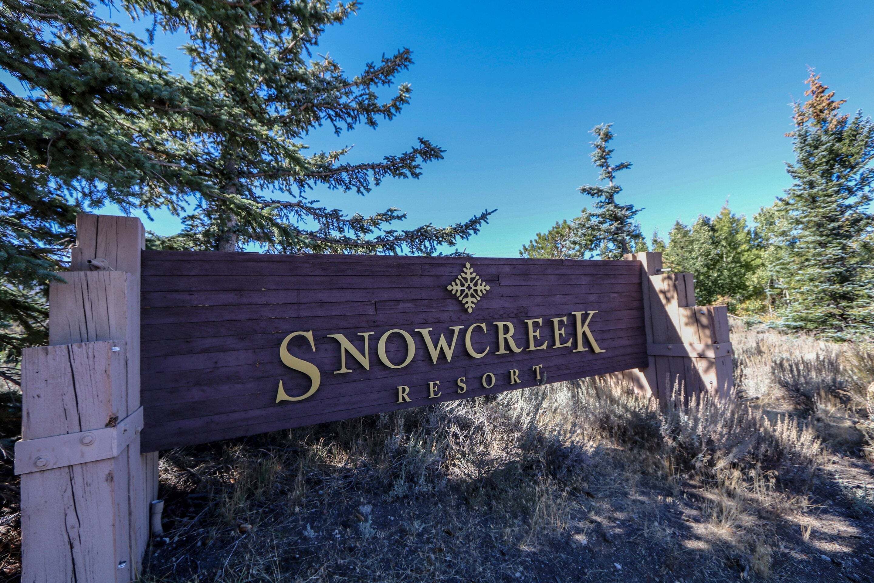 Señal de madera del complejo turístico Snow Creek, con cielo despejado al fondo.
