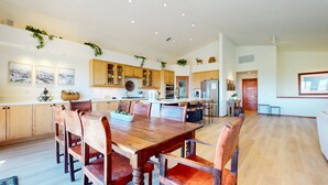Una cocina amplia con armarios de madera, una isla central y un comedor con sillas de madera.
