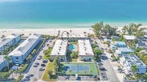 Ein Luftbild eines Küstenhotels mit Pool, Tennisplatz und Zugang zum Strand.