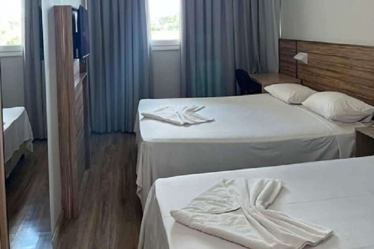 Een hotelkamer met twee bedden, een houten hoofdbord, een nachtkastje en een spiegel.
