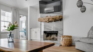 A modern living room with a wooden coffee table, a fireplace, a grey sofa, and a TV mounted on the wall. - Welcome to Your Fairhope Getaway! (Fairhope)