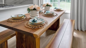 A wooden dining table with placemats, plates, and vases of flowers. - Welcome to Your Fairhope Getaway! (Fairhope)