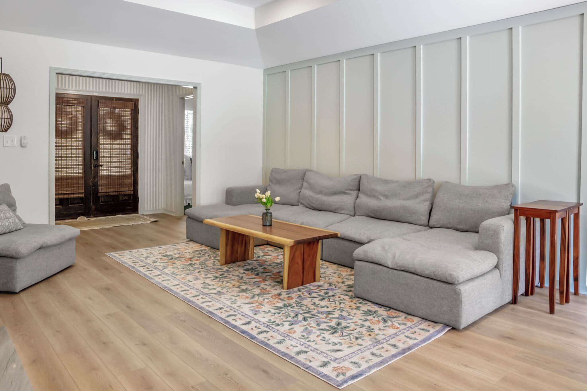 Un soggiorno moderno con un divano grigio, un tavolino in legno e un tappeto decorato.