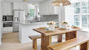 A modern kitchen with white cabinetry, a wooden dining table, and a large window. - Welcome to Your Fairhope Getaway! (Fairhope)