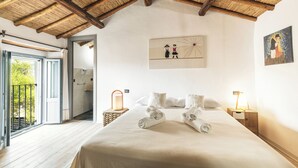 Un dormitorio con techo de madera, una cama con toallas dobladas, lámparas de noche y un cuadro en la pared.