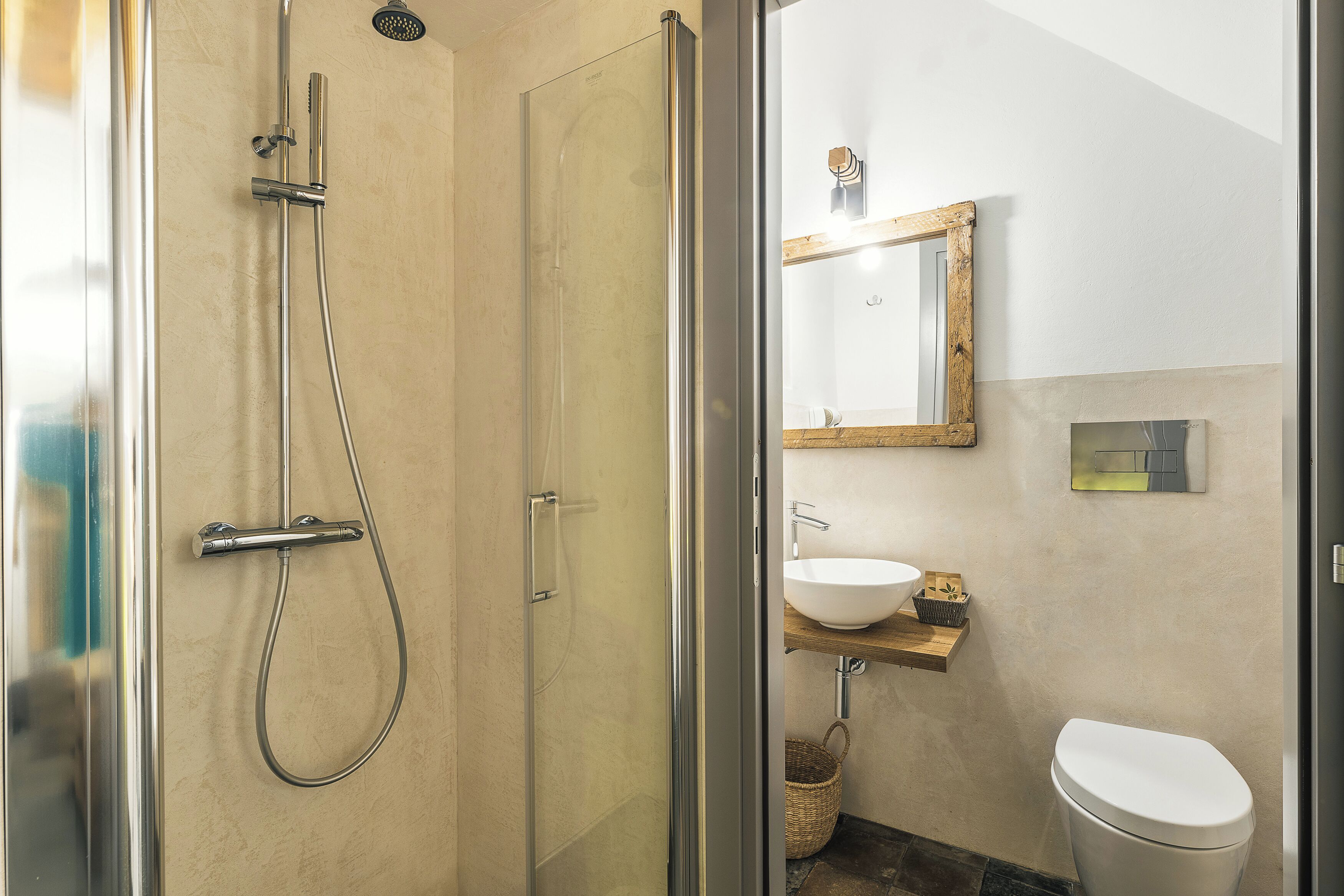 Une salle de bain avec une douche à parois de verre, un lavabo blanc et une étagère en bois.