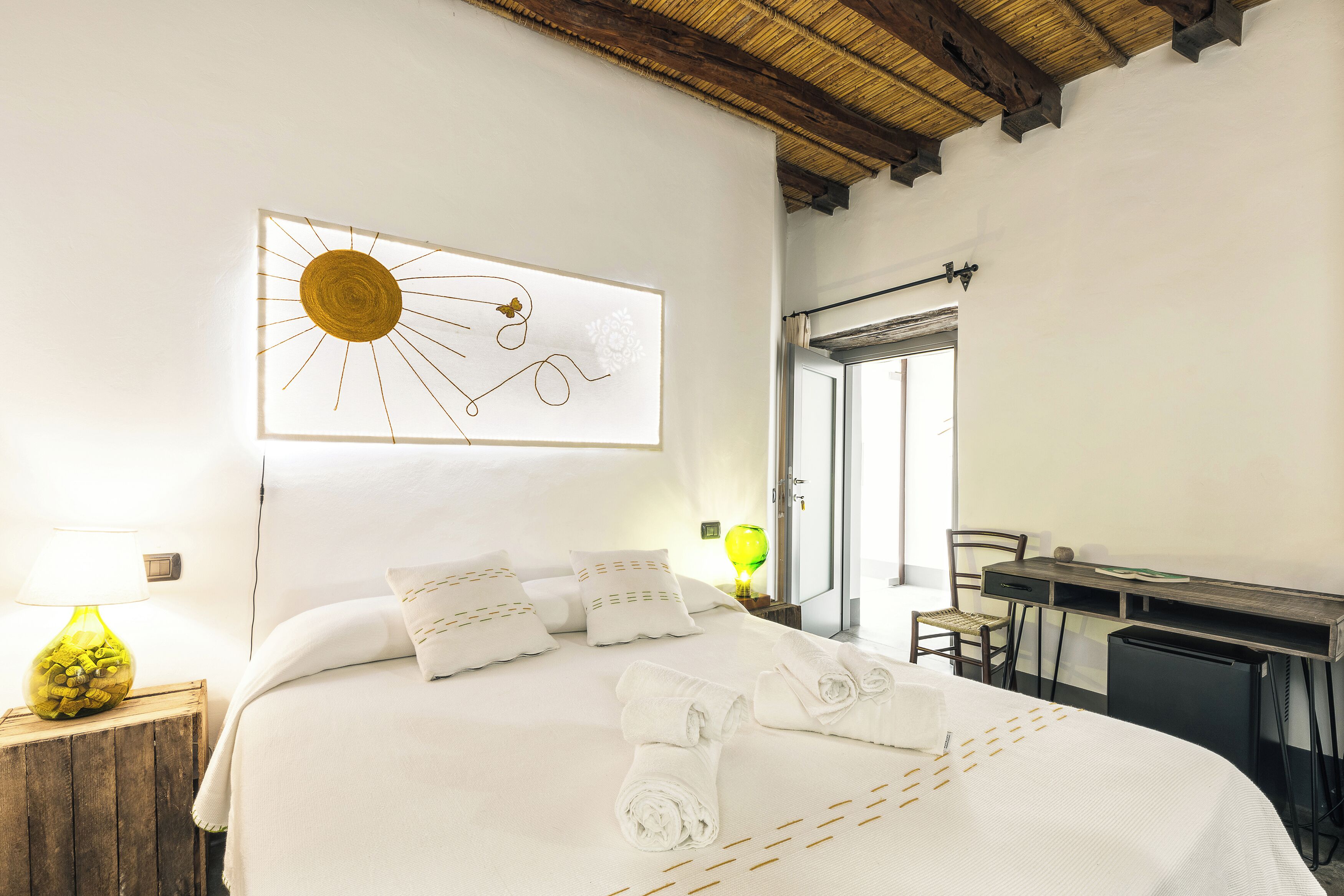 Une chambre d’hôtel comprenant un lit, un bureau, une chaise, une lampe et une œuvre d’art murale.