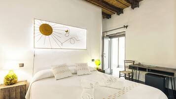 Une chambre d’hôtel comprenant un lit, un bureau, une chaise, une lampe et une œuvre d’art murale.
