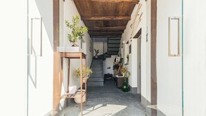 Un pasillo estrecho con techo de madera, una escalera y plantas en macetas.