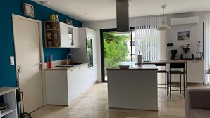 Una cocina moderna con armarios blancos, una isla central y una zona de comedor con mesa y sillas.