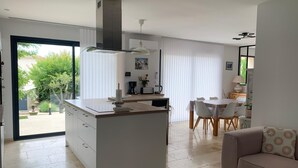 Una cocina moderna con una isla central, un comedor con mesa y sillas, y una sala de estar con sofá.