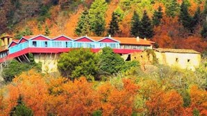 A building with a red roof and blue walls, surrounded by autumn foliage. - Goura Guesthouse Mountain Double Suite Lake Doxa (Goura)