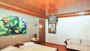 A bedroom with a wooden ceiling, a bed, a white sofa, and three paintings on the wall. - Goura Guesthouse Mountain Twin Suite Lake Doxa (Goura)