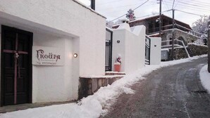 A building with a sign reading "KROUZA" and a stone wall. - Goura Guesthouse Mountain Twin Suite Lake Doxa (Goura)