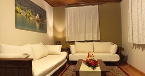 A living room with two sofas, a coffee table with a floral arrangement, and a painting of a lake.