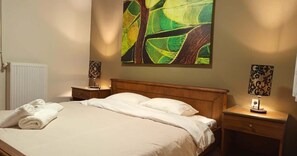 A hotel room with a bed, a nightstand, a lamp, and a painting on the wall.