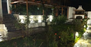 A courtyard with a stone pathway, a small water feature, and a barbecue area.