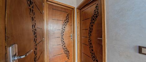 A hallway with two wooden doors featuring intricate black patterns.