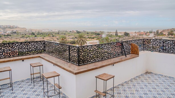A rooftop terrace with a patterned floor, a decorative railing, and a view of a distant landscape. - House Aisha (Tamraght)