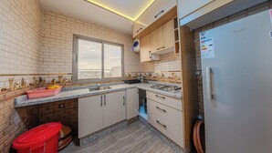 A modern kitchen with a brick backsplash, granite countertops, and a built-in oven. - House Aisha (Tamraght)