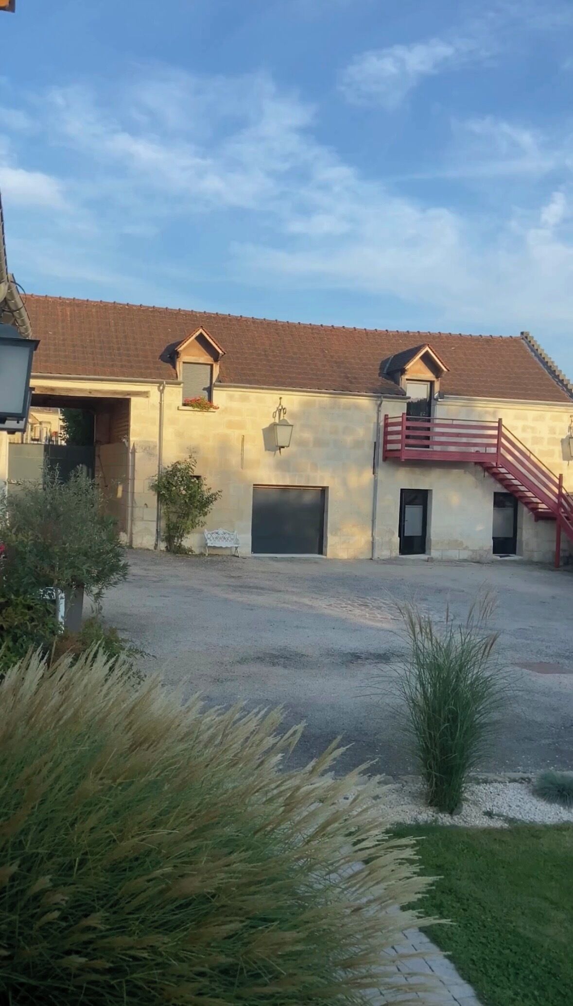 A building with a red-tiled roof, a red staircase, and a garage door.