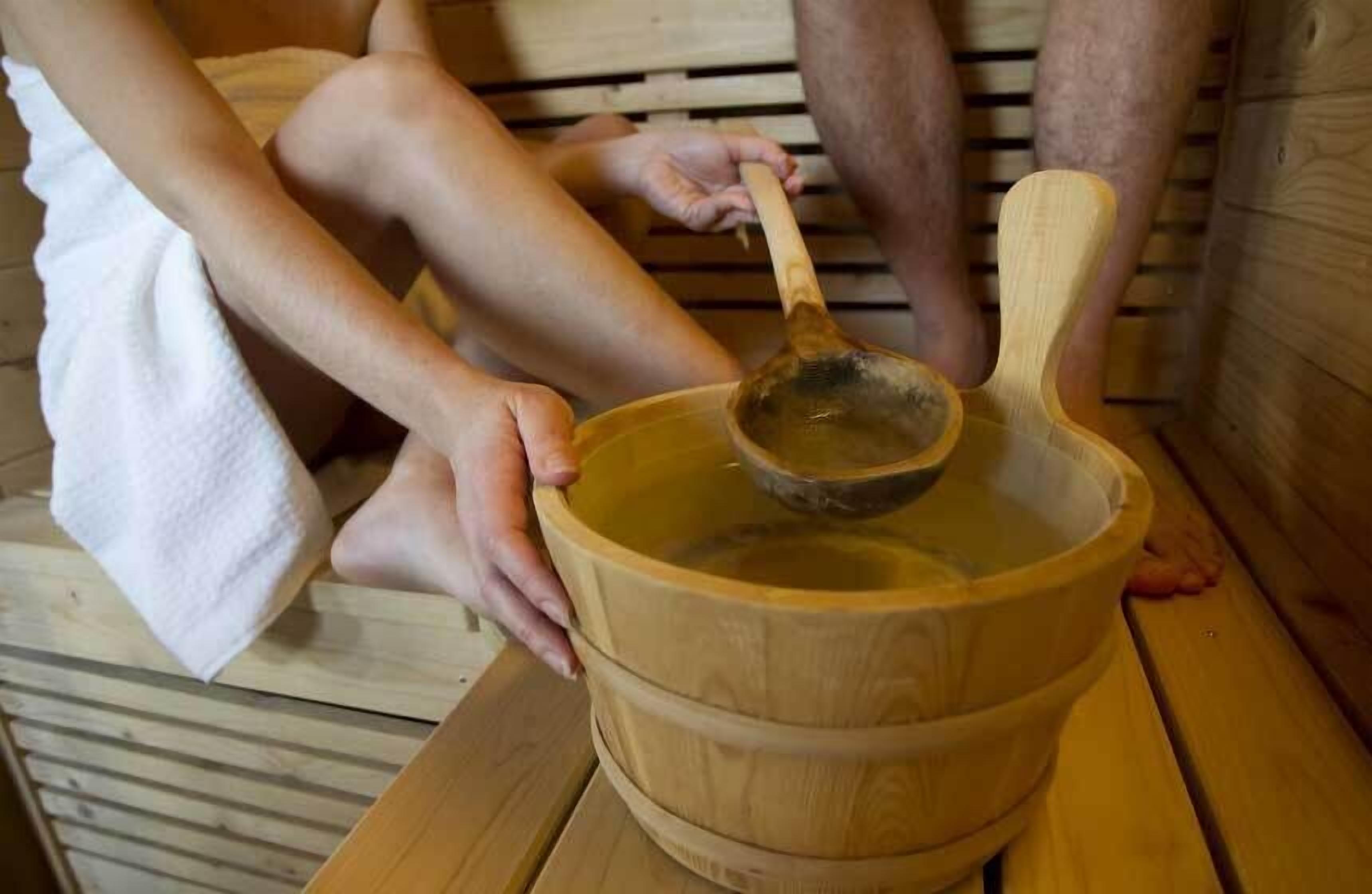 Una tina de madera con una cuchara, probablemente utilizada para un baño relajante o de inmersión.