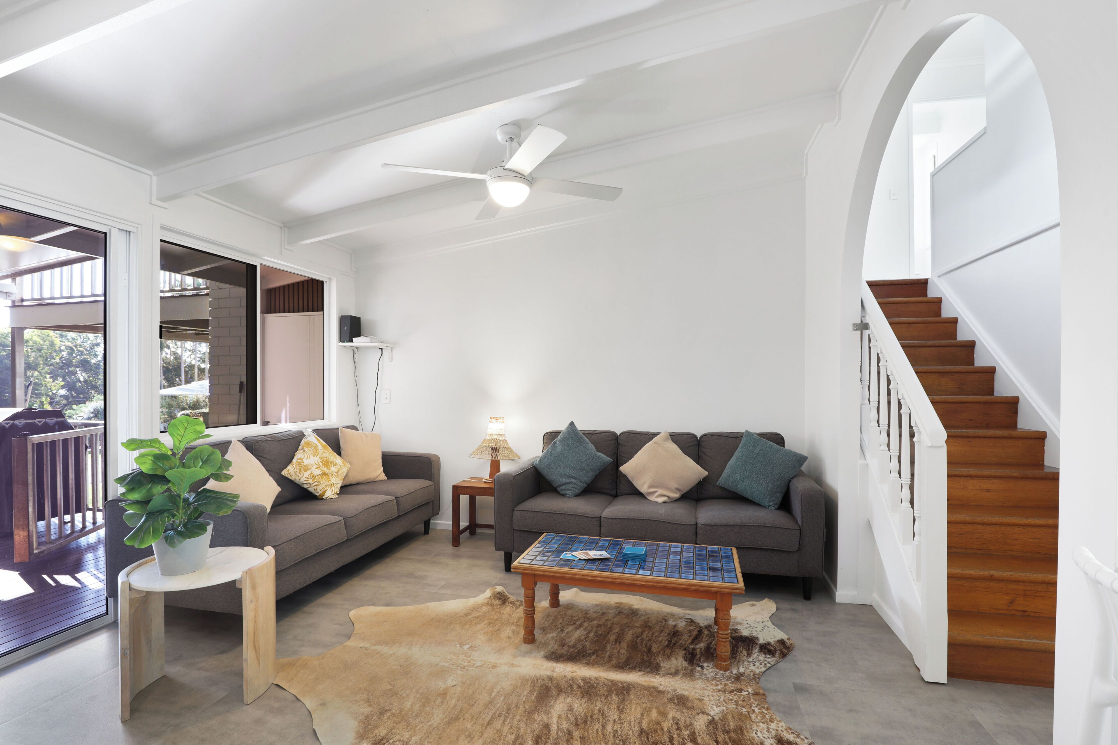 A modern living room with a grey sofa, a coffee table, and a staircase.