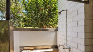 A small, enclosed outdoor area with a brick wall and a metal railing, surrounded by greenery.