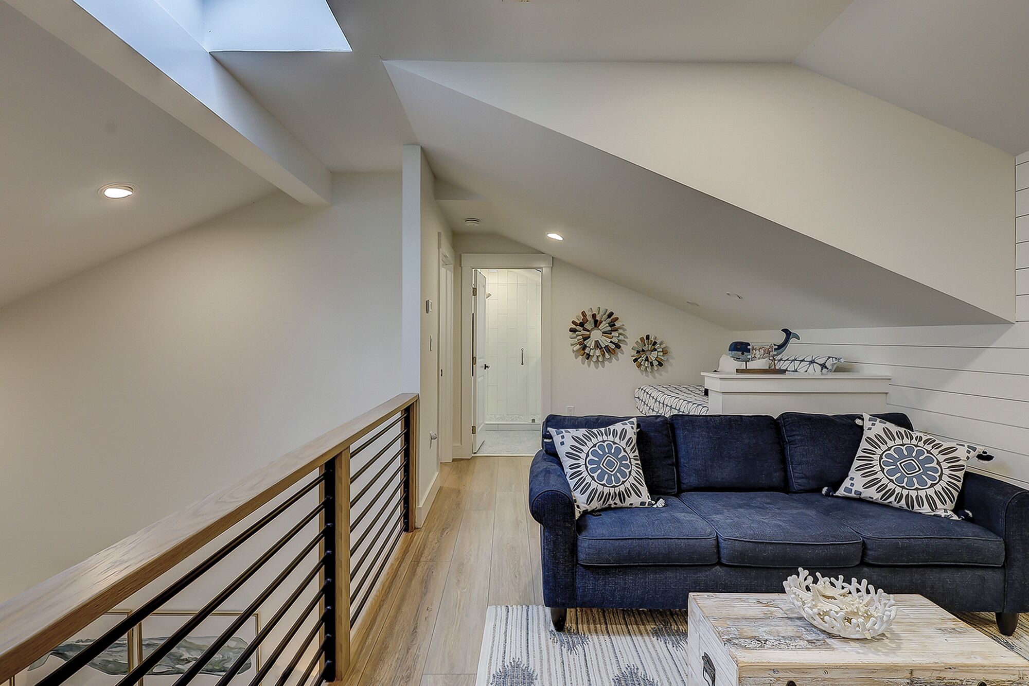 Une chambre de style loft moderne avec un plafond en pente, un canapé bleu foncé agrémenté de coussins à motifs et un bol décoratif posé sur une table en bois.