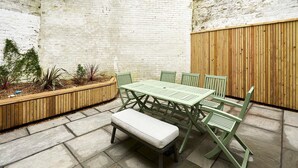 A patio with a green table and chairs, a bench, and a planter with plants. - Host and Stay Prospect Rise (Hastings)