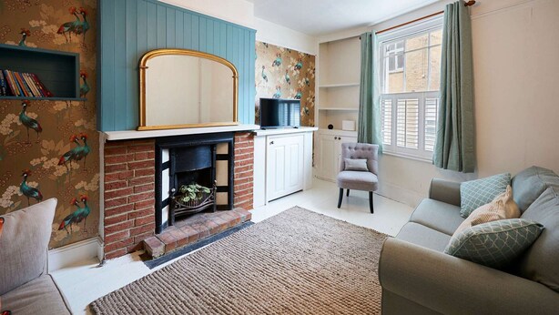 A living room with a fireplace, a sofa, a chair, and a television. - Host and Stay Prospect Rise (Hastings)