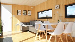 A modern interior with wooden panel walls, a sofa, white chairs, a table, and framed pictures. - The Saltkrokan Houseboat in the Archipelago of Southern Sweden (Blankaholm)
