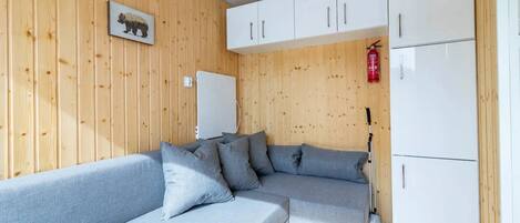 A modern room with a grey sectional sofa, white cabinets, and a wooden wall with a bear picture.