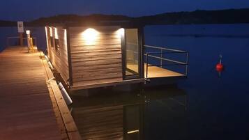 Une jetée en bois s’étendant sur une étendue d’eau calme, au crépuscule.