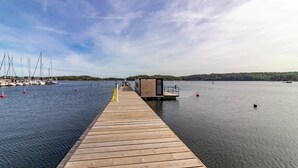 A wooden pier leading to a dock with boats and a small wooden structure. - The Saltkrokan Houseboat in the Archipelago of Southern Sweden (Blankaholm)