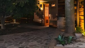 Un patio empedrado con un edificio de madera que tiene una puerta y una escalera.