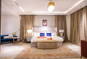 A modern bedroom with a large bed, a blue sofa, and a chandelier. - Sujimoto Serviced Apartments (Lagos)