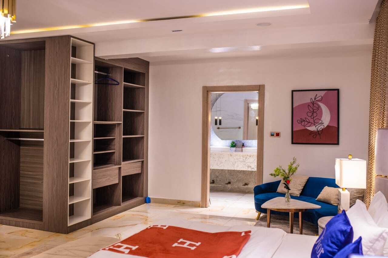 Une chambre d’hôtel moderne, dotée d’une grande armoire, d’un canapé, d’une table basse et d’un tableau au mur.