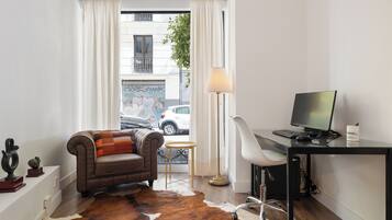 A modern room with a leather sofa, a desk with a computer, a cowhide rug, and a view of the street outside.