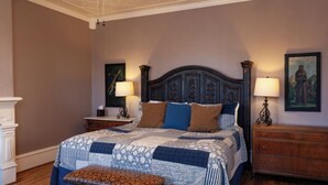 Une chambre à coucher avec un grand lit, deux tables de chevet, un banc et une commode.