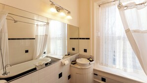 Une salle de bain avec une baignoire, un lavabo, un miroir et une fenêtre avec un rideau de douche.