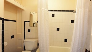 Une salle de bain équipée de toilettes, d’une baignoire et d’un rideau de douche.