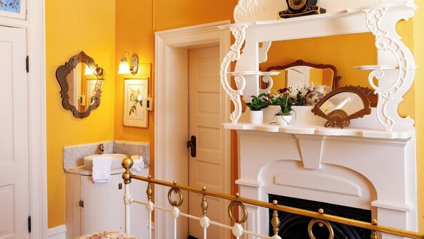 Une salle de bain avec une baignoire blanche, un miroir et une étagère ornée d’objets décoratifs.
