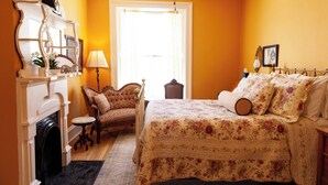 Une chambre à coucher avec un lit, une chaise, une cheminée et une fenêtre.