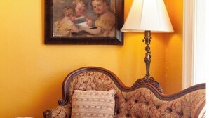 Une pièce avec un canapé à motifs, une petite table ronde, une lampe et un tableau encadré accroché au mur.