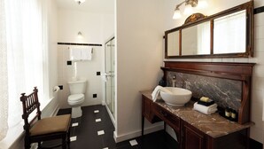 A bathroom with a toilet, sink, and mirror. - William F. Cody - Historic Hotel Room (Cimarron)