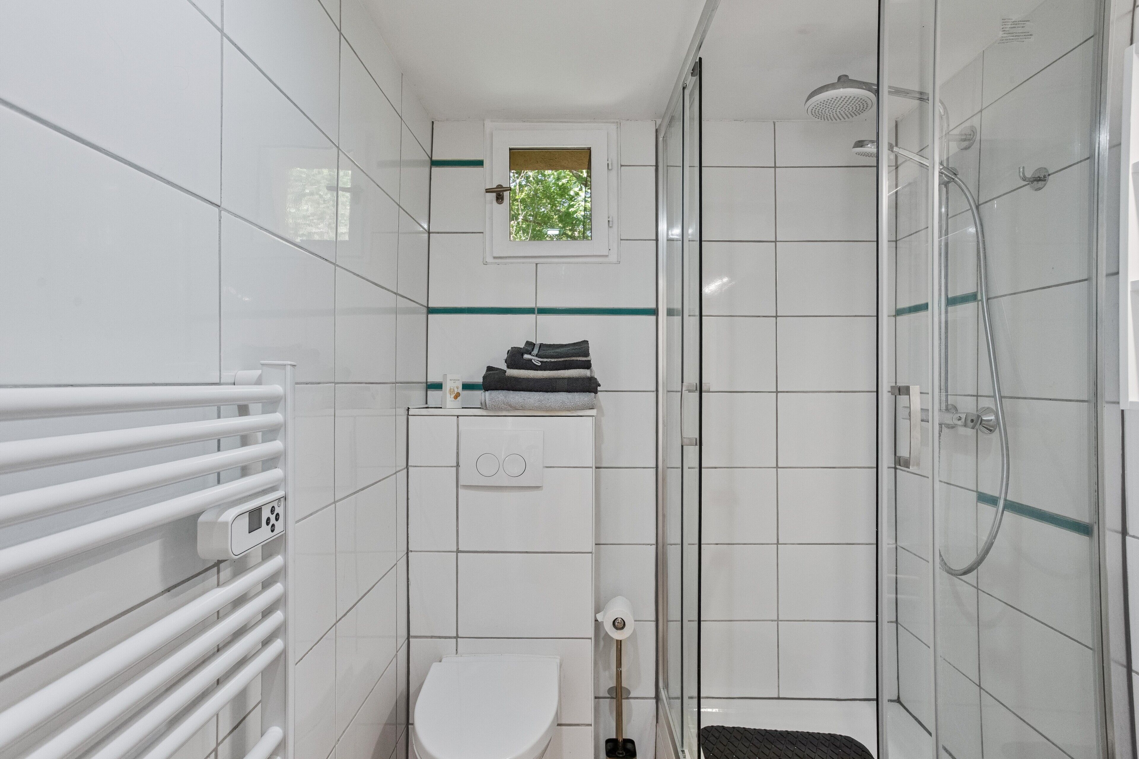 A modern bathroom with a glass shower enclosure, a toilet, and a towel rack.